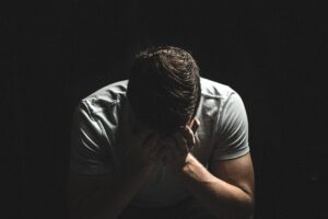 Sad man sitting in the dark with his head down.