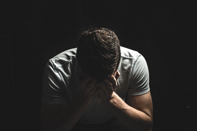 Sad man sitting in the dark with his head down.